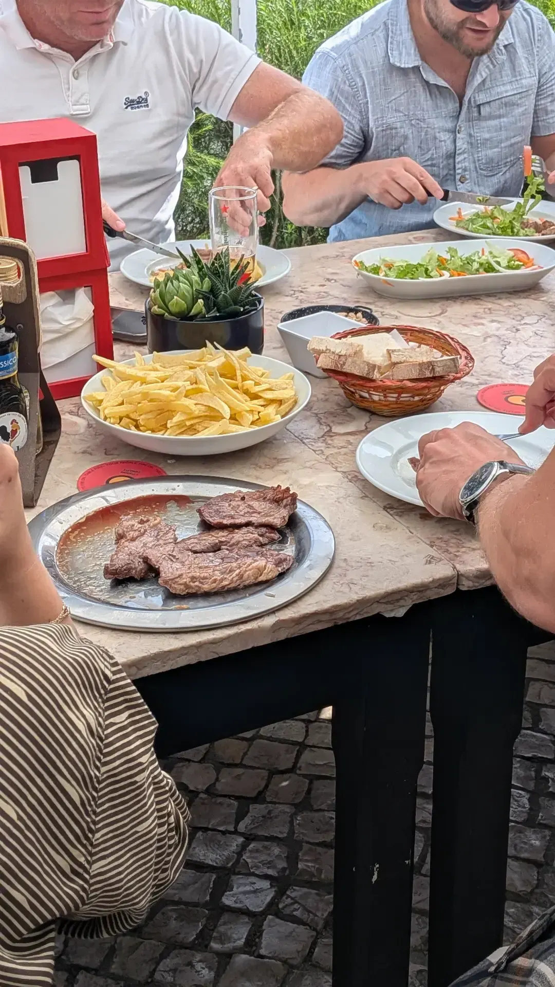 Mesa de churrasco com carne grelhada, batatas fritas e salada